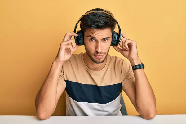 Νεαρός Όμορφος Άντρας Που Ακούει Μουσική Φορώντας Ακουστικά Σκεπτικός Και — Φωτογραφία Αρχείου