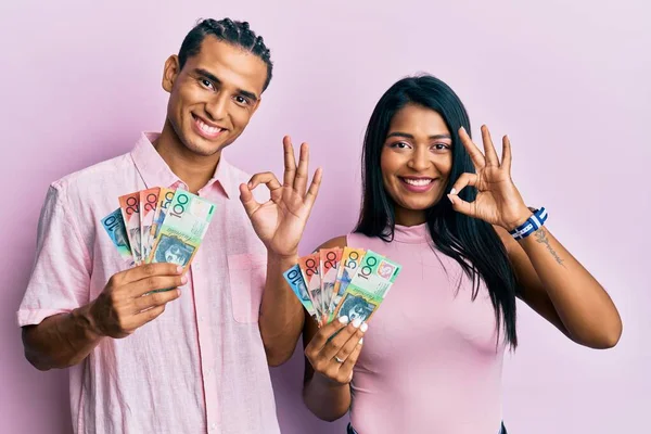 Jovem Casal Latino Segurando Dólares Australianos Fazendo Sinal Com Dedos — Fotografia de Stock