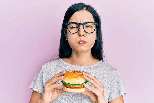 Beautiful Young Woman Eating Tasty Hamburger Puffing Cheeks Funny Face — Stock Fotó