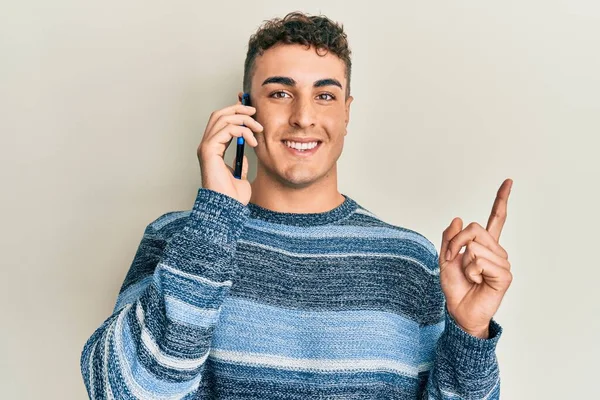 Hispánský Mladý Muž Který Mluví Smartphonu Šťastně Usmívá Ukazuje Rukou — Stock fotografie