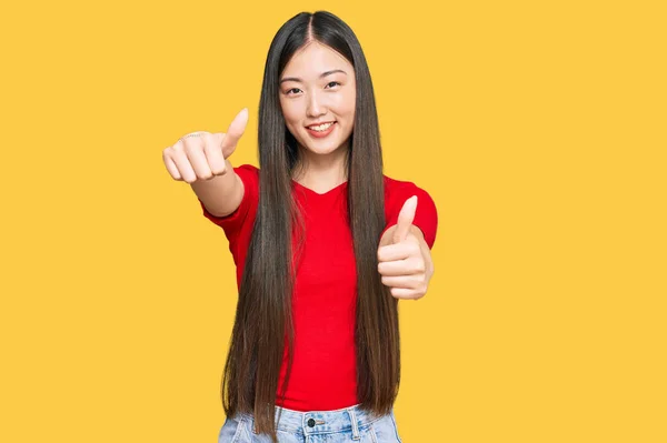 年轻的中国女人穿着休闲装 赞成用手做一个积极的手势 微笑着竖起大拇指 为成功感到高兴 优胜手势 — 图库照片