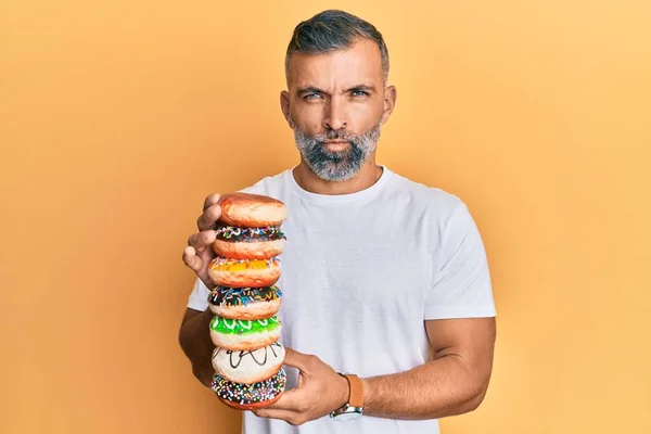 Middle Age Handsome Man Holding Tasty Colorful Doughnuts Skeptic Nervous — Stock Photo, Image