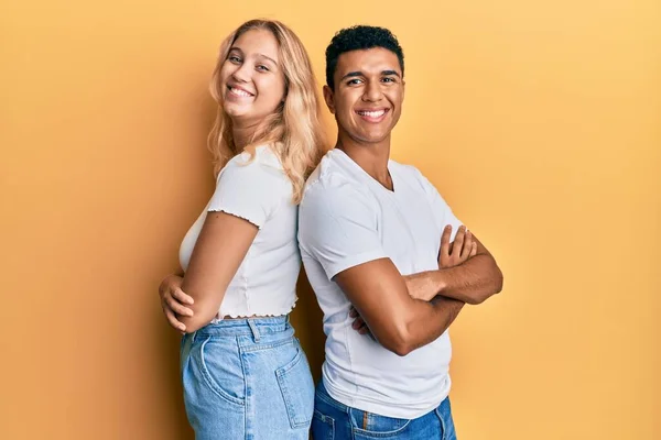 年轻的跨种族夫妇穿着休闲的白色T恤 高兴地面带微笑 双臂交叉地看着相机 积极的人 — 图库照片