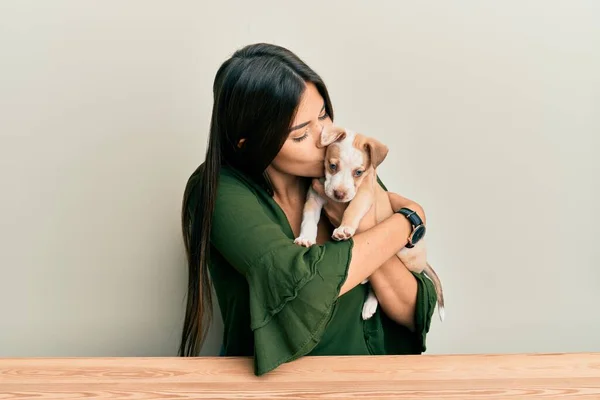 Menina Hispânica Jovem Abraçando Beijando Cão Sentado Mesa Sobre Fundo — Fotografia de Stock