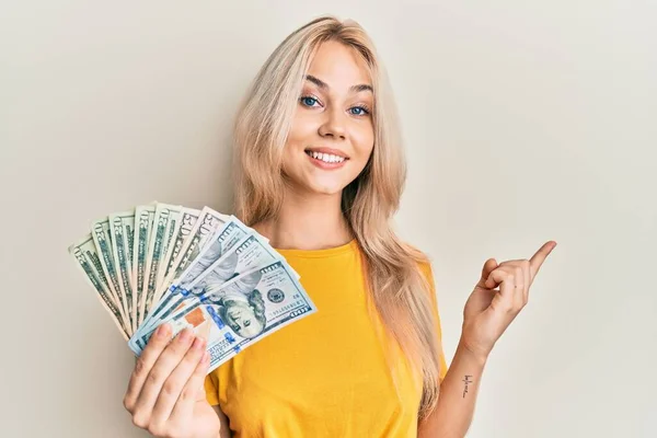 Krásná Kavkazské Blondýny Dívka Drží Dolary Úsměvem Šťastný Ukazující Rukou — Stock fotografie