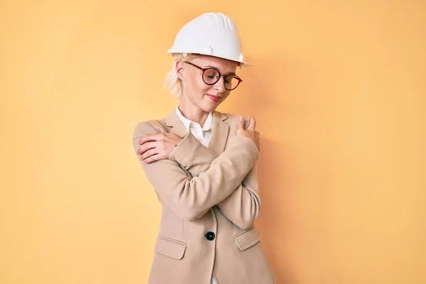 Young Blonde Woman Wearing Architect Hardhat Hugging Oneself Happy Positive — Stock Fotó