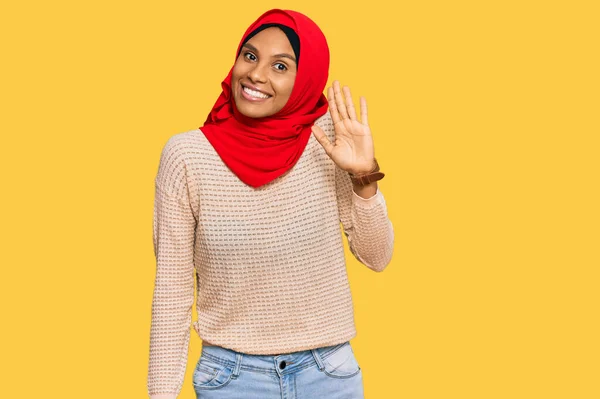 伝統的なイスラム教のヒジャーブスカーフを身に着けている若いアフリカ系アメリカ人の女性はこんにちは幸せと笑顔 優しい歓迎のジェスチャーを言う — ストック写真