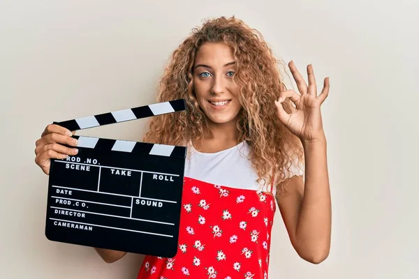 Beautiful Caucasian Teenager Girl Holding Video Film Clapboard Doing Sign — Fotografia de Stock