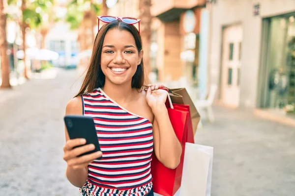 Młoda Latynoska Dziewczyna Shopper Trzyma Torby Zakupy Pomocą Smartfona Mieście — Zdjęcie stockowe