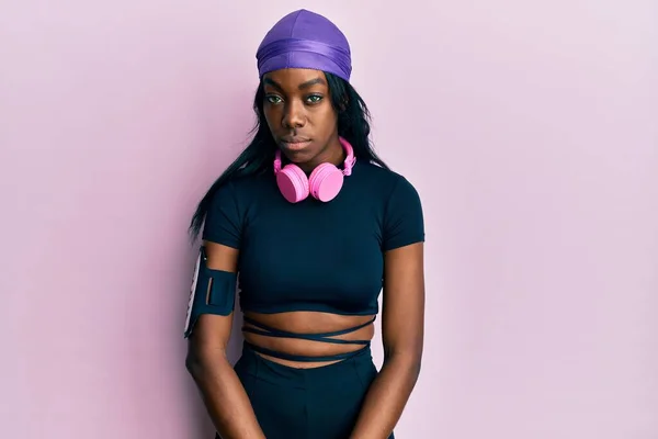 Young African American Woman Wearing Gym Clothes Using Headphones Skeptic — Stockfoto