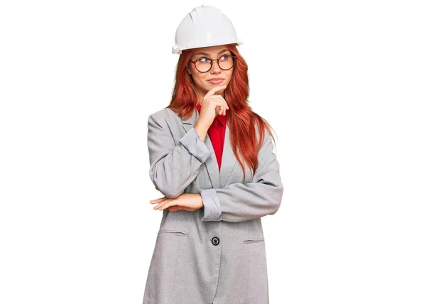 Young Redhead Woman Wearing Architect Hardhat Hand Chin Thinking Question — Stok fotoğraf