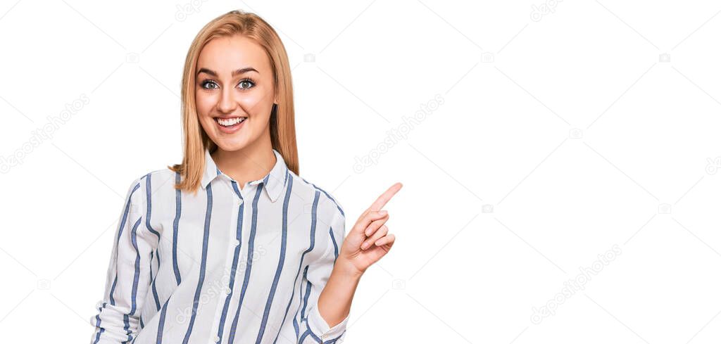 Beautiful caucasian woman wearing casual clothes with a big smile on face, pointing with hand finger to the side looking at the camera. 