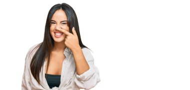 Gündelik giysiler giymiş genç, güzel İspanyol bir kız. El ve burunla işaret ediyor. Neşeli gülümsüyor. güzellik konsepti 