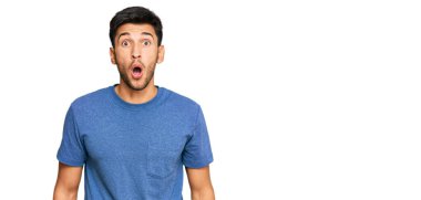 Gündelik giysiler giyen genç yakışıklı adam korkmuş ve ağzı açık kalmış, şaşırmış ve şaşırmış. 