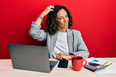 Ofiste çalışan orta yaşlı güzel bir kadın bir fincan kahve içiyor ve soru soruyor. Şüpheyle kararsız, kafa kafaya düşünerek. Düşünceli kavram. 