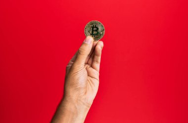 Genç İspanyol el, bitcoin 'i izole edilmiş kırmızı arka planda tutuyor..