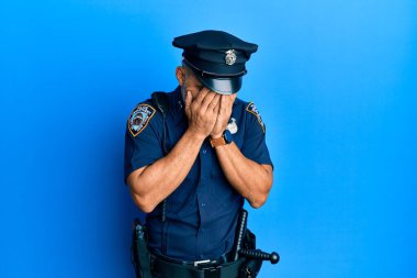 Orta yaşlı, yakışıklı, polis üniforması giyen, suratını ellerle örten ve ağlayan bir adam. depresyon kavramı. 