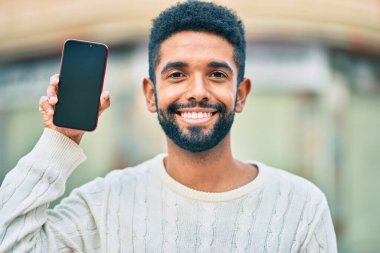 Genç Afrikalı Amerikalı adam gülümsüyor. Şehre akıllı telefon gösterdiği için mutlu..