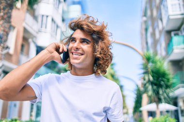 Genç İspanyol adam şehrin caddesinde akıllı telefondan konuşuyor.