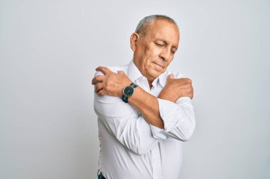 Yakışıklı, beyaz gömlek giyen, kendine sarılan mutlu ve pozitif, kendinden emin gülümseyen bir adam. Sevgi ve özgüven. 