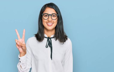 İş gömleği ve gözlük takan güzel Asyalı genç bir kadın kameraya bakıp gülümsüyor ve zafer işareti yapıyor. İki numara.. 