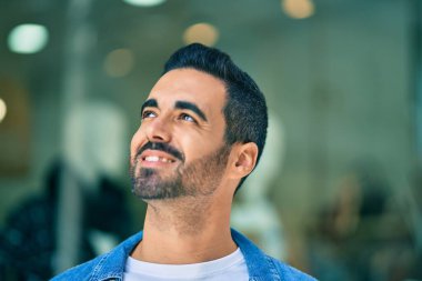 Genç İspanyol adam gülümseyerek şehirde mutlu mesut dikiliyor..