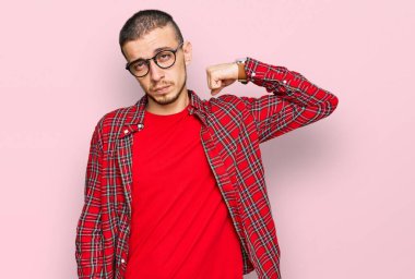 Hispanik genç adam günlük kıyafetler giyiyor güçlü biri kol kası gösteriyor, kendinden emin ve gururlu. 