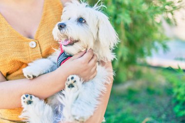 Parkta sevimli beyaz köpeğe sarılan bir kadın..