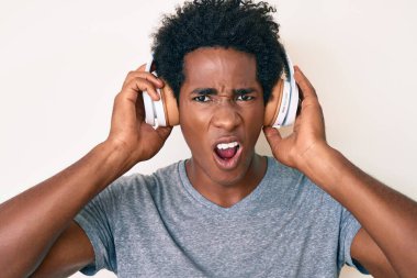 Yakışıklı Afro saçlı, müzik dinleyen, kulaklık takan, kuşkucu, alaycı ve ağzı açık bir şekilde şaşırmış Afro-Amerikan erkeği. 