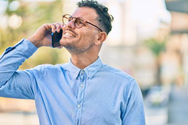 Genç İspanyol işadamı gülümsüyor. Şehirdeki akıllı telefondan mutlu bir şekilde konuşuyor..