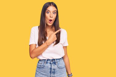 Gündelik beyaz tişört giyen genç İspanyol kadın parmaklarını yana doğru göstererek şaşırdı, ağzı açık hayret içinde kaldı.. 