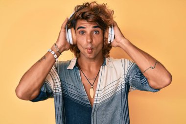 Genç İspanyol adam kulaklık takıp müzik dinliyor. Ağızla balık suratı yapıyor ve şaşı bakıyor. Deli ve komik.. 