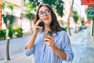 Ciddi bir suratı olan genç İspanyol iş kadını şehirdeki akıllı telefondan konuşuyor..