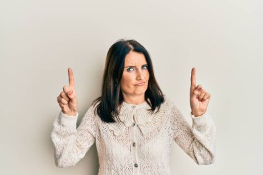 Orta yaşlı esmer kadın şüpheci ve gergin parmaklarıyla işaret ediyor, sorun yüzünden kaşlarını çatıyor. negatif kişi. 