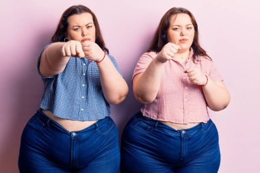 Genç ve cüsseli ikizler gündelik kıyafetler giyip dövüşmek için yumruklarını yumrukluyor agresif ve öfkeli saldırılar, tehdit ve şiddet. 