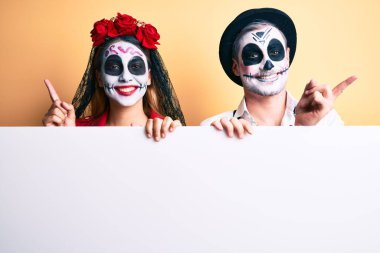 Ölü kostümün giyildiği gün ellerinde boş pankartlar olan çift gülümsüyor mutlu bir şekilde elleri ve parmakları yana doğru işaret ediyor. 