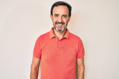 Orta yaşlı İspanyol bir adam mutlu ve havalı bir gülüşü olan sıradan kıyafetler giyiyor. şanslı kişi. 