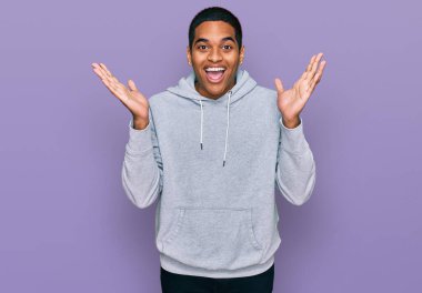 Genç, yakışıklı, sıradan bir tişört giyen, çılgın ve başarıyı kolları açık, gözleri açık, heyecanlı bir şekilde kutlayan İspanyol bir adam. Kazanan konsept 