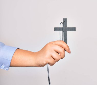 Beyaz arka planda Hıristiyan haçı tutan Kafkasyalı genç katolik kadının eli