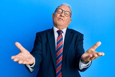 Beyaz üst düzey bir adam takım elbise ve kravat takıyor. Gülümsüyor, yardım eli uzatıyor ve kabul ediyor.. 