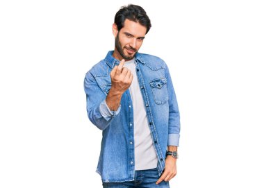 Gündelik giysiler giyen genç İspanyol adam seni buraya davet ediyor. Elinle mutlu bir şekilde karşılamaya ve gülümsemeye davet ediyor. 