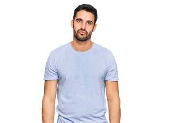 Latin asıllı genç bir adam, günlük giysiler içinde kameraya bakıyor ve güzel ve seksi bir şekilde havadan öpücük yolluyor. aşk ifadesi. 