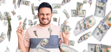 Sıradan kıyafetler giyen genç yakışıklı adam umut ve gözlerin kapalı gülümseyerek el sallıyor. Şans ve batıl inançlar.