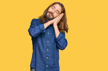 Uzun saçlı ve sakallı çekici bir adam. Günlük giysiler giyiyor. Yorgun uyuyor.. 