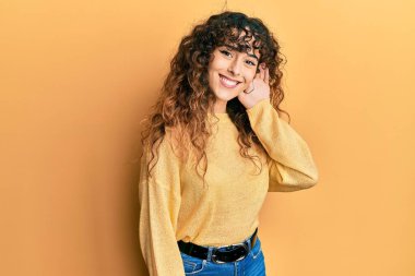 Günlük kıyafetler giyen, ağzı kulaklarında gülümseyen genç İspanyol kız dedikoduları ve dedikoduları dinliyor. Sağırlık kavramı. 