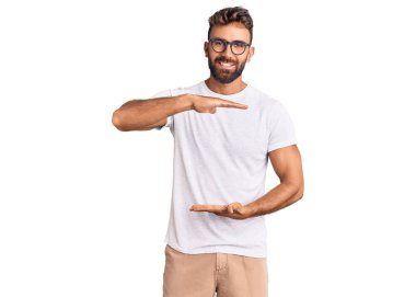 Gündelik kıyafetler giyen ve büyük boy ve ölçü işareti gösteren el kol hareketleri yapan Latin kökenli genç bir adam. Kameraya bakıp gülümsüyor. ölçüm kavramı. 