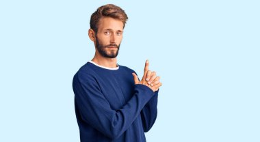 Sarışın, sakallı, sıradan bir kazak giyen, el hareketleriyle sembolik bir silah tutan, cinayet silahlarıyla oynayan, sinirli yüzlü yakışıklı bir adam. 