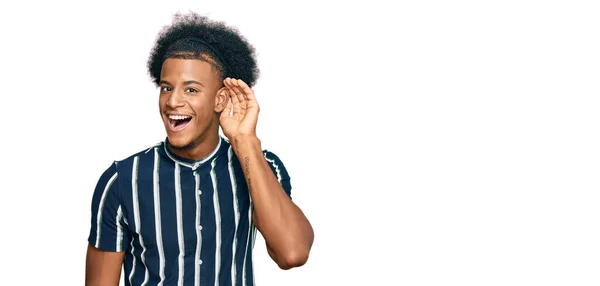 アフリカ系アメリカ人の男性のアフロヘアは 噂やゴシップに耳を傾ける耳に手で笑みを浮かべてカジュアルな服を着ている 聴覚障害の概念 — ストック写真