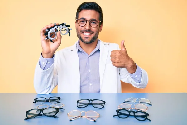 Joven Hombre Hispano Sosteniendo Gafas Óptica Sonriendo Feliz Positivo Pulgar — Foto de Stock