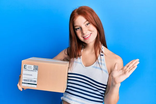 Menina Cabeça Vermelha Jovem Segurando Pacote Entrega Celebrando Realização Com — Fotografia de Stock